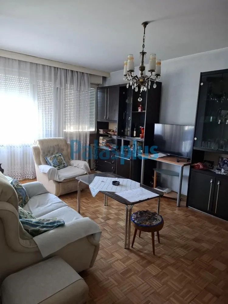 Dnevna soba sa garniturom, TV-om i trpezarijskim stolom.