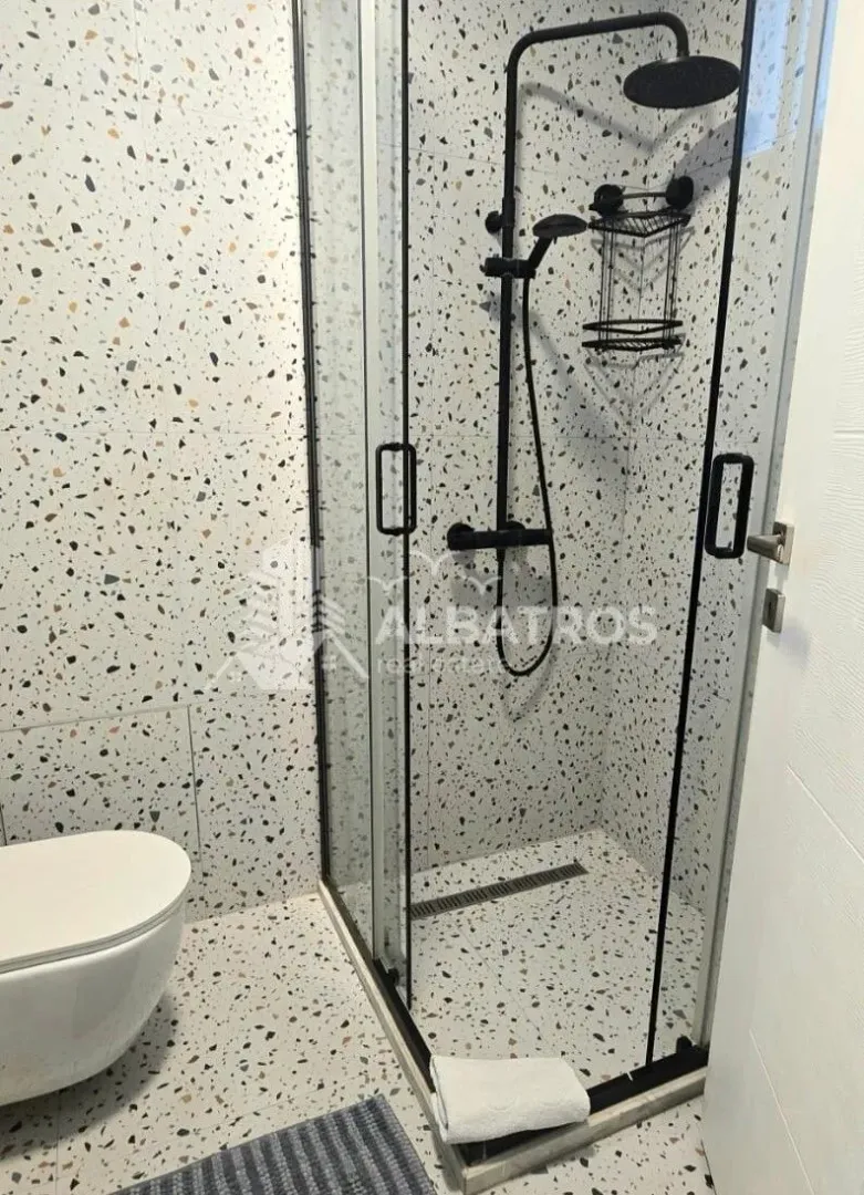 Bathroom with a walk-in shower and terrazzo tiles.