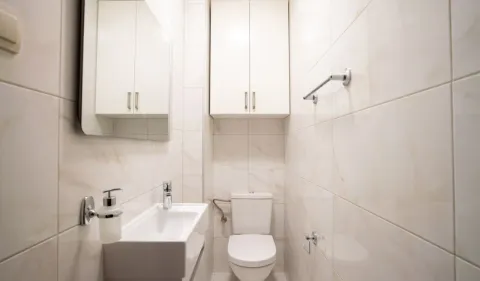 Manje kupatilo obloženo svijetlim pločicama sa umivaonikom i toaletom. - image 19