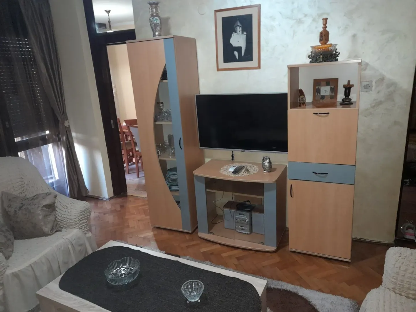 Dnevna soba sa televizorom, komodom i garniturom za sjedjenje.