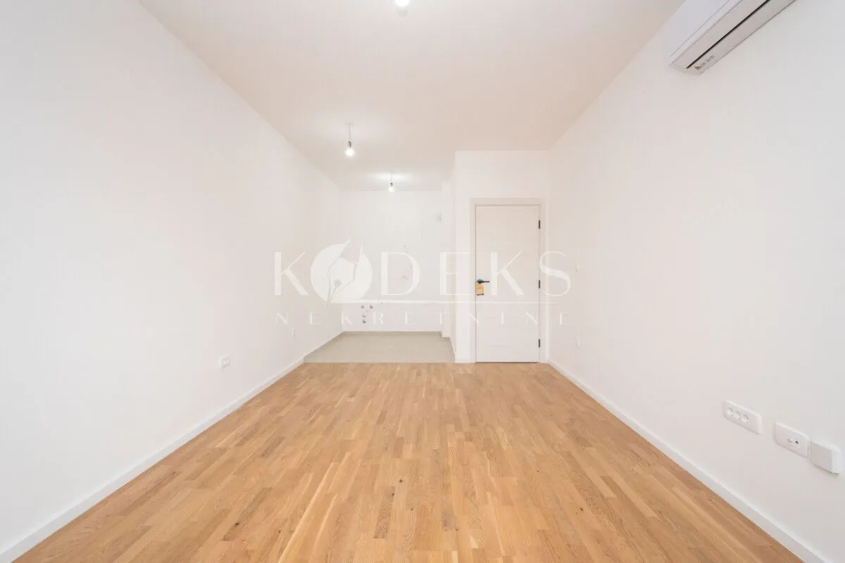 Empty bright room with hardwood flooring and an air conditioner.