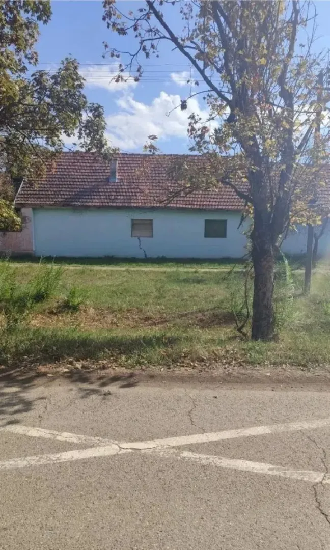 Pogled na prizemnu kuću sa dvorištem i putem u prvom planu.