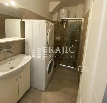 Bathroom with a shower cabin, sink, and washing machine. - image 8