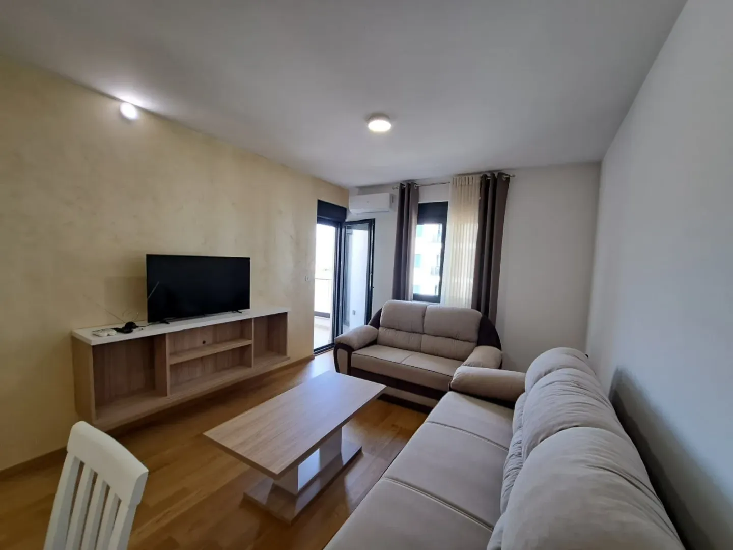 Living room with sofas, TV unit and access to the balcony.