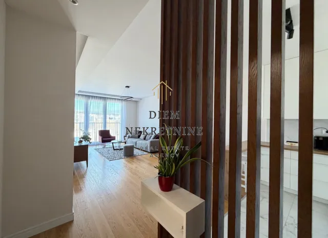 View from the hallway into a bright living room and kitchen separated by wooden partition slats.