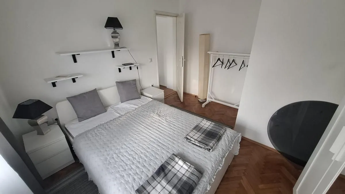 Spavaća soba sa bračnim krevetom, noćnim stočićima i drvenim podom.