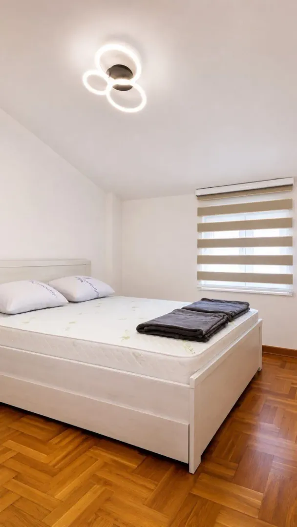 Bright bedroom with a double bed and parquet flooring.