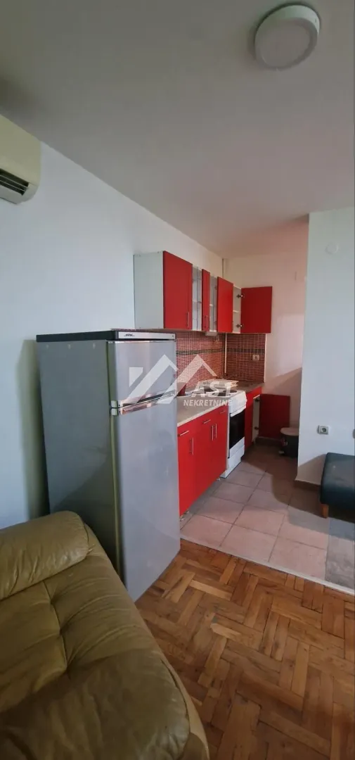 Kuhinja opremljena crvenim elementima i frižiderom.