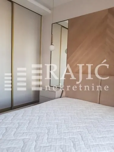 Modern bedroom with a double bed, built-in wardrobe, and wooden wall panel.