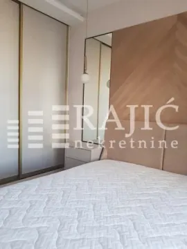 Modern bedroom with a double bed, built-in wardrobe, and wooden wall panel. - image 3