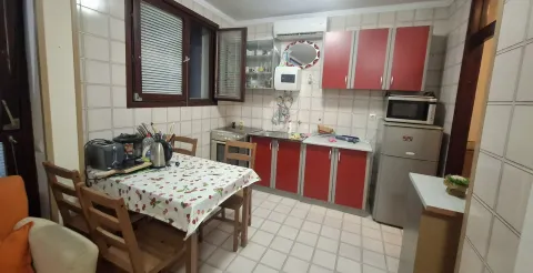 Trpezarija sa kuhinjom opremljena elementima crvene boje i trpezarijskim stolom. - image 11