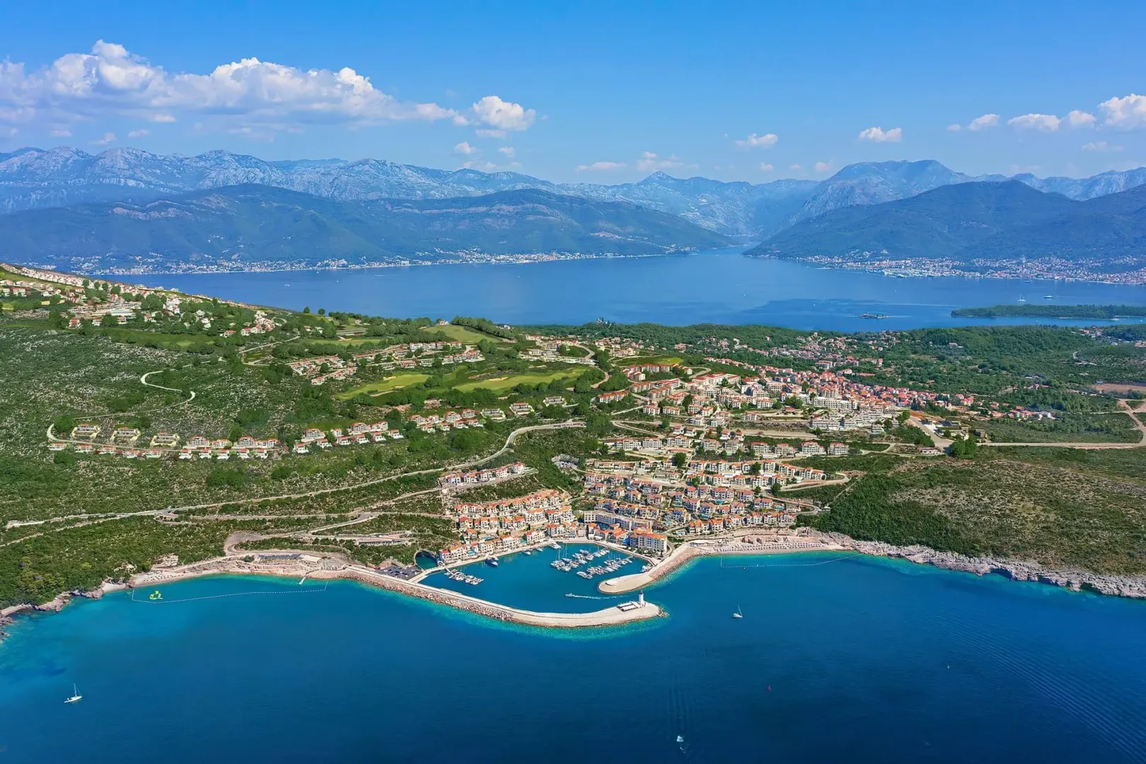 Pogled iz vazduha na zaliv, marinu i okolni pejzaž.