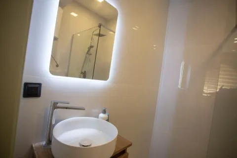 Modern bathroom equipped with a washbasin and an illuminated mirror. - image 8