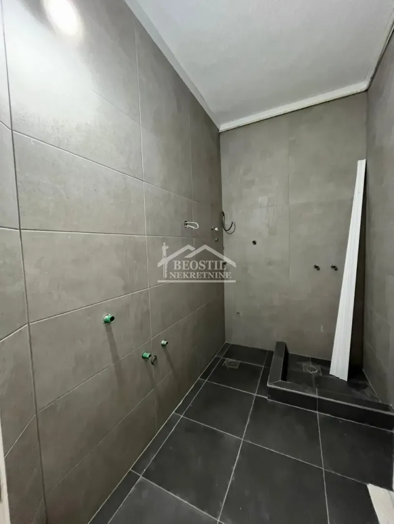 Kupatilo u fazi renoviranja obloženo sivo-crnim pločicama.