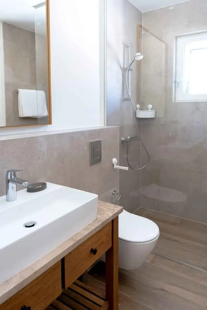 Savremeno opremljeno kupatilo sa umivaonikom, tuš kabinom i wc šoljom.