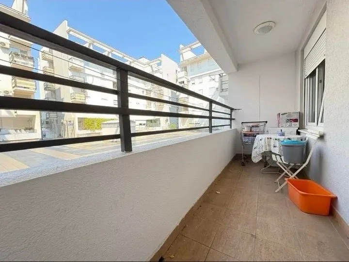 Covered balcony space with railing and a view of buildings.