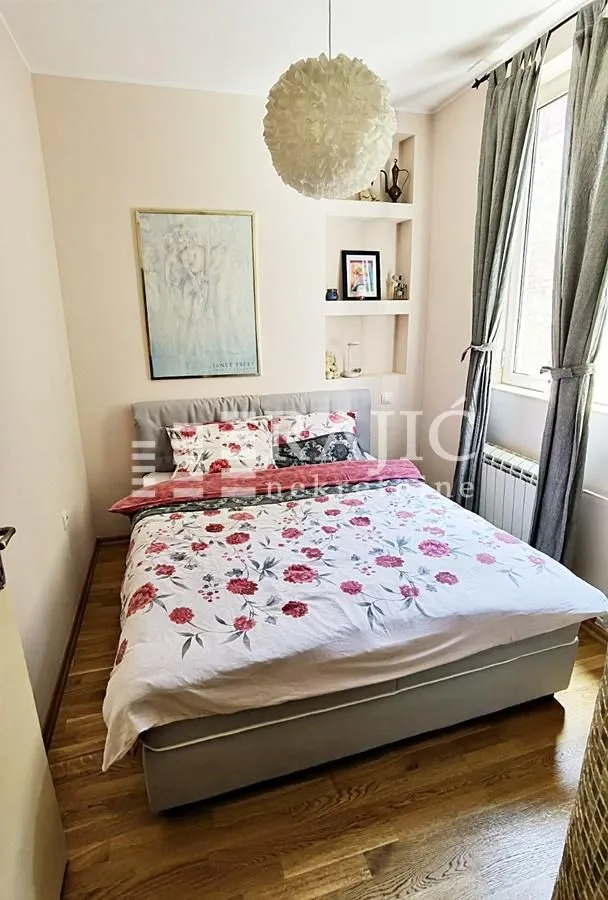 Furnished bedroom with a double bed, window, and built-in wall niches.