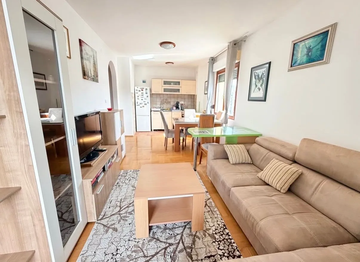 Living room connected with the dining area and kitchen in the background.