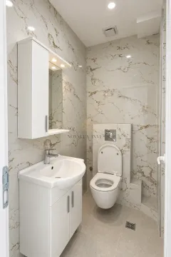 Modern bathroom with white sanitary ware and marble-patterned tiles. - image 5