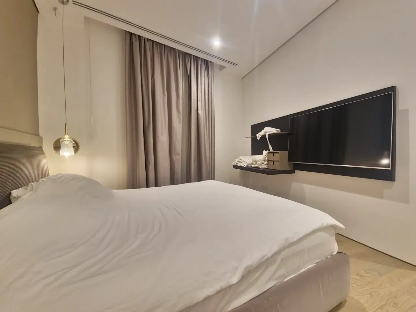 Modern bedroom with a double bed, curtains, and a wall-mounted TV.
