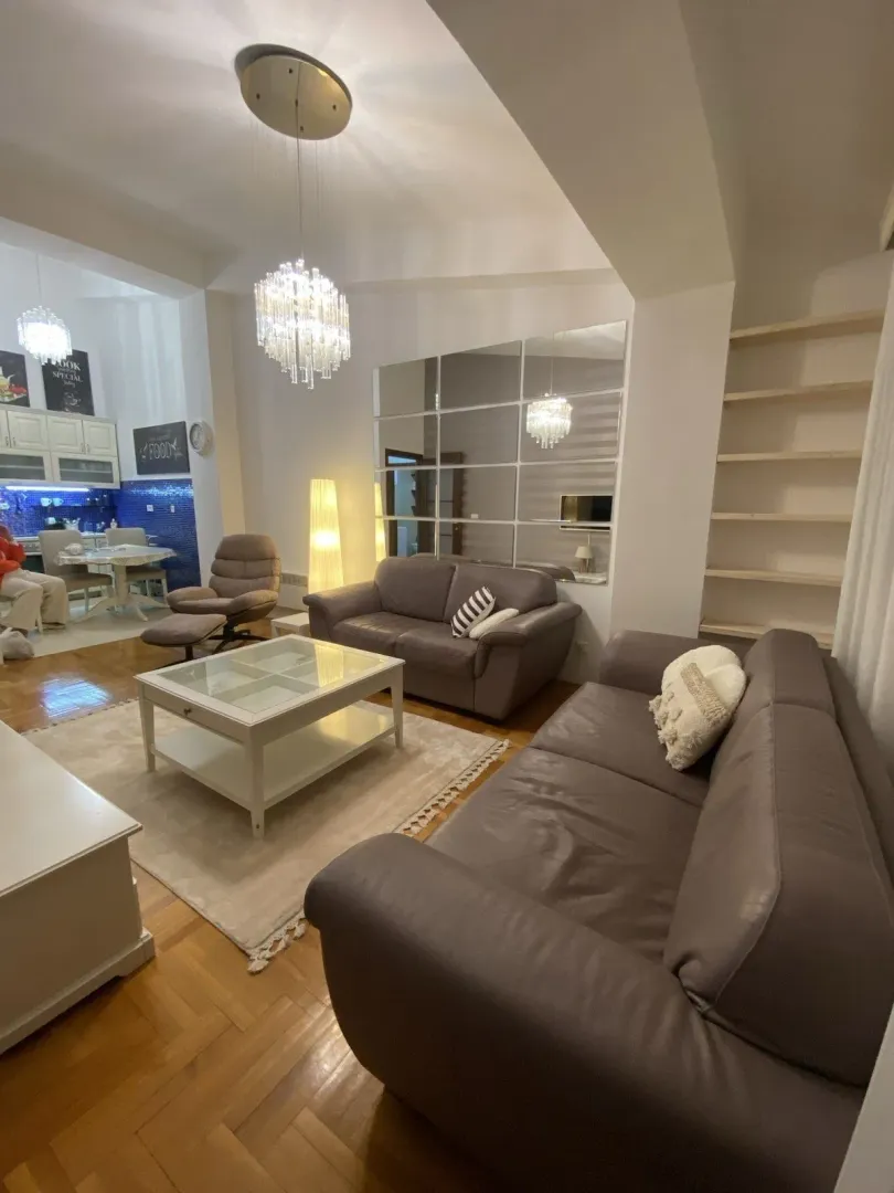 Bright living room with leather sofas, a coffee table, and wall mirrors.