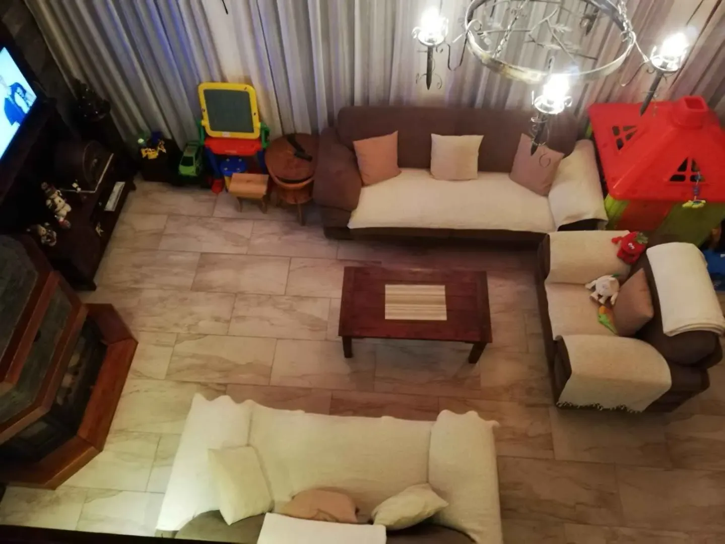 Pogled odozgo na prostranu dnevnu sobu sa garniturom, kaminom i igračkama za djecu.