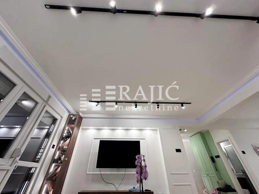 View of the ceiling and living room wall with lighting and a television.