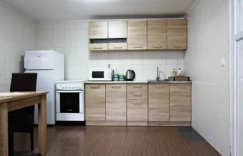 Kuhinja sa drvenim elementima, frižiderom, šporetom i trpezarijskim stolom. - image 11