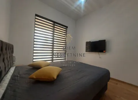 Namještena spavaća soba sa bračnim krevetom, televizorom i prozorom sa roletnama. - image 8