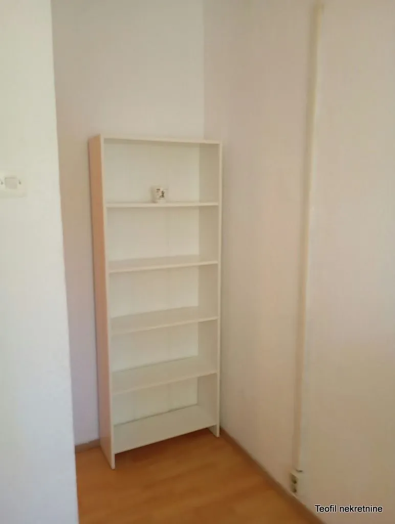 White bookshelf in the corner of a room with wooden flooring.