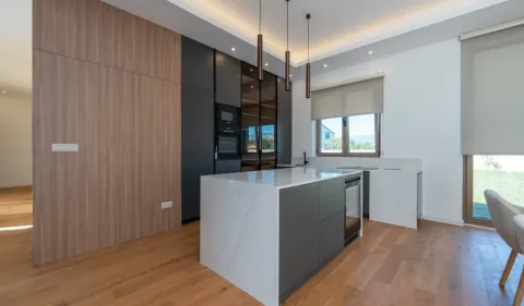 Modern kitchen with an island, built-in appliances and dining table. - image 4
