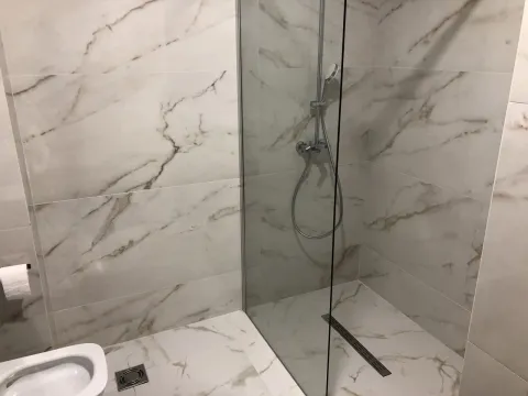 Modern bathroom featuring a walk-in shower with marble-look tiles. - image 2