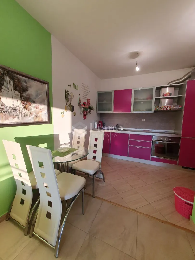 Kitchen with a dining area and pink cabinets.