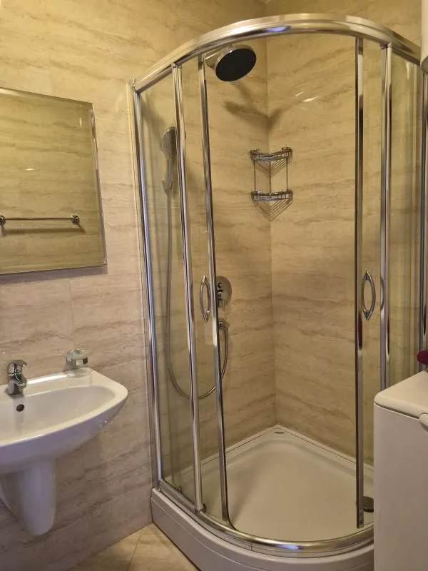 Kupatilo sa tuš kabinom, umivaonikom i ogledalom.