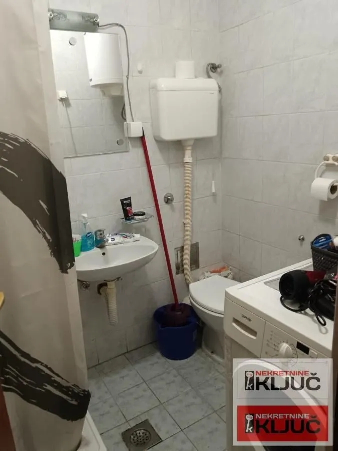 Manje kupatilo sa umivaonikom, WC šoljom i veš mašinom.