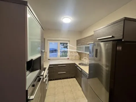 Separate kitchen with dark wooden cabinetry and built-in appliances. - image 5