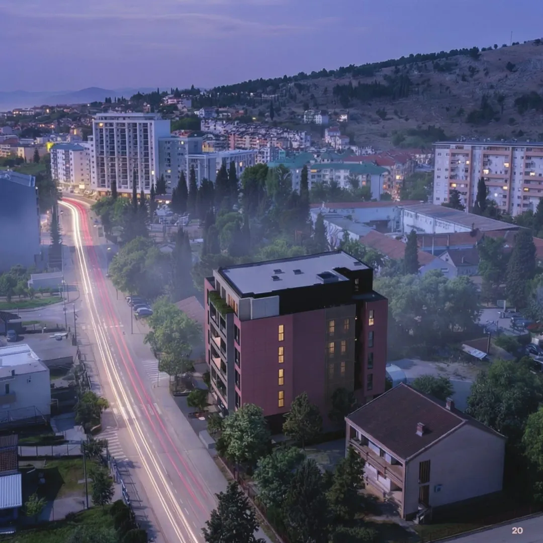 Aerial view of a new residential building and the surrounding neighborhood at dusk.