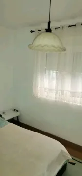 A simple bedroom featuring a window and a hanging light. - image 8