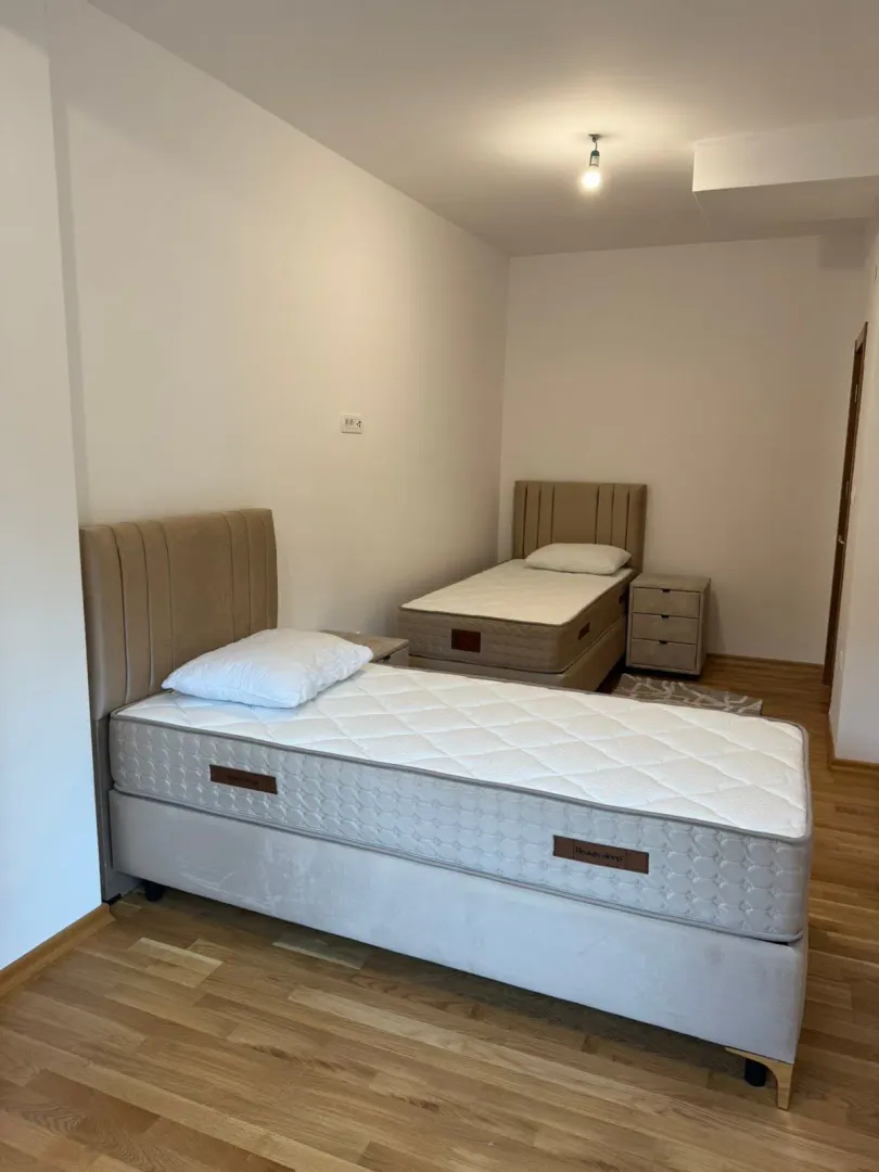 Spavaća soba sa dva kreveta i noćnim stočićem.