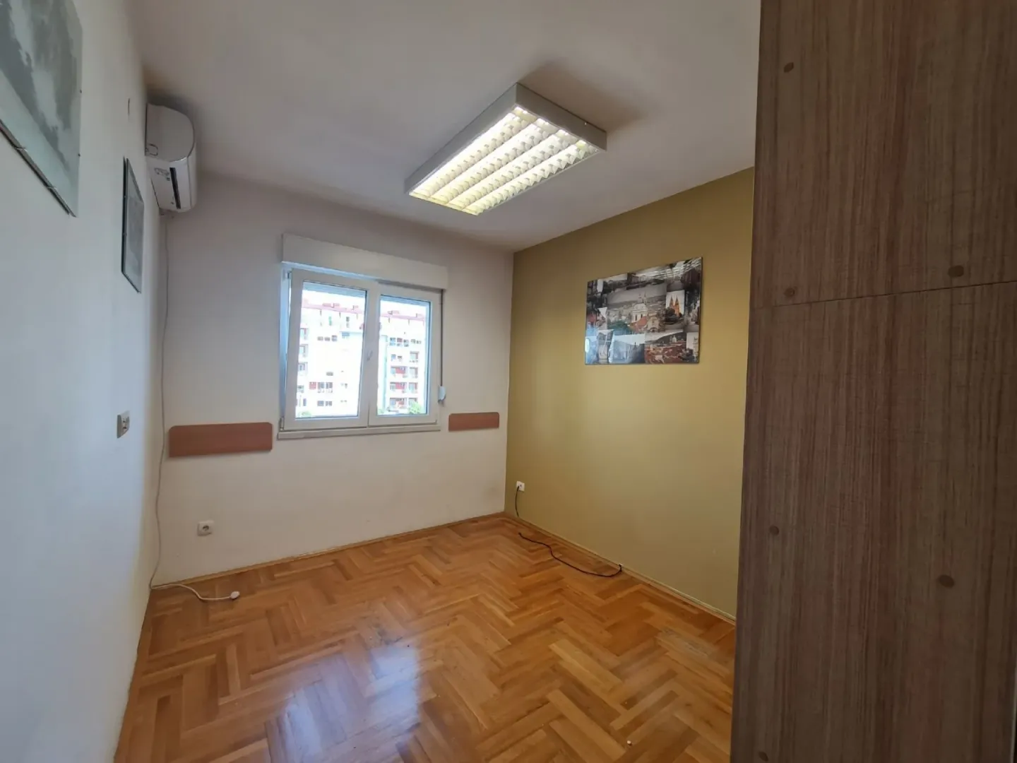 An empty room with parquet flooring and air conditioning.