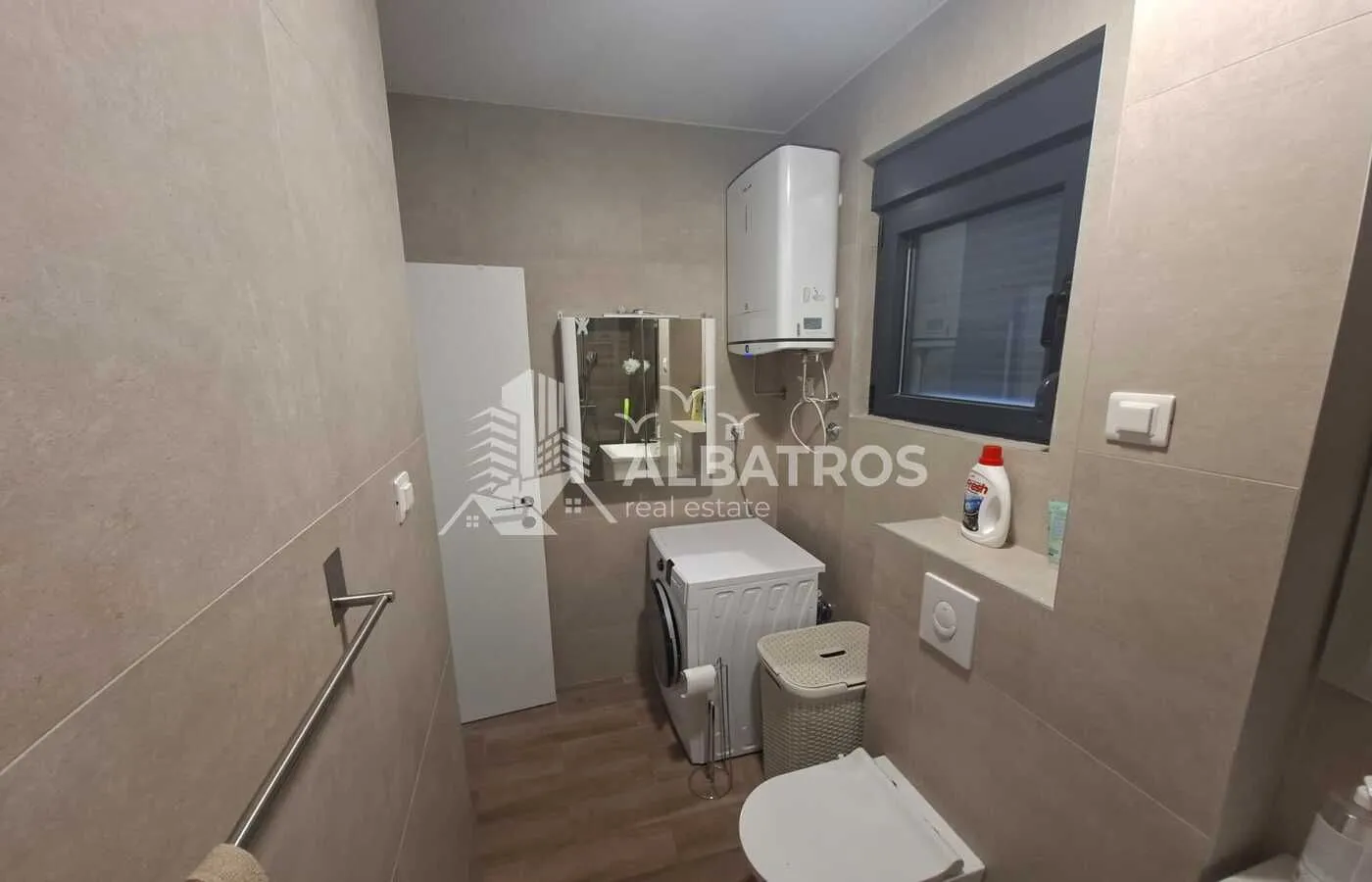 Moderne kupatilo sa tuš kabinom, veš mašinom i WC šoljom.