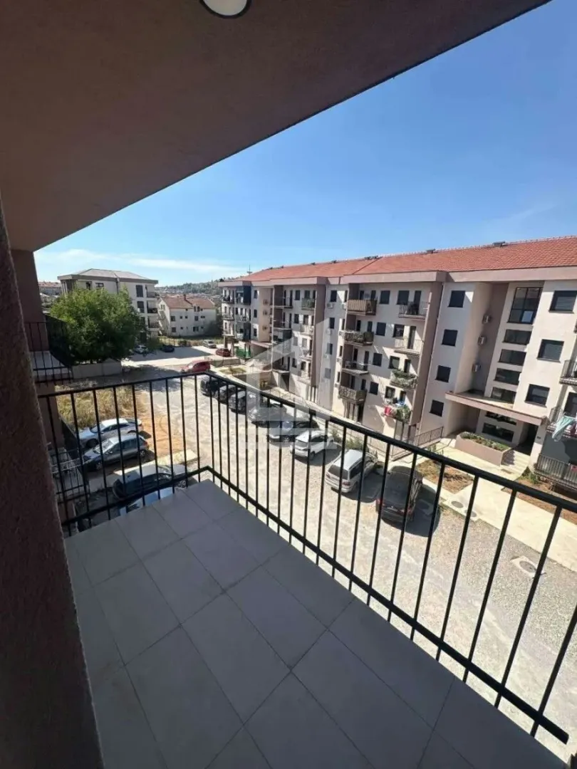 Pogled sa balkona na okolne zgrade i parking.