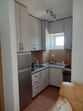 Mala funkcionalna kuhinja sa bijelim elementima i frižiderom. - image 3