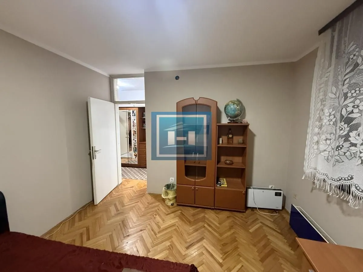 Furnished bedroom with wooden parquet flooring and a wardrobe.