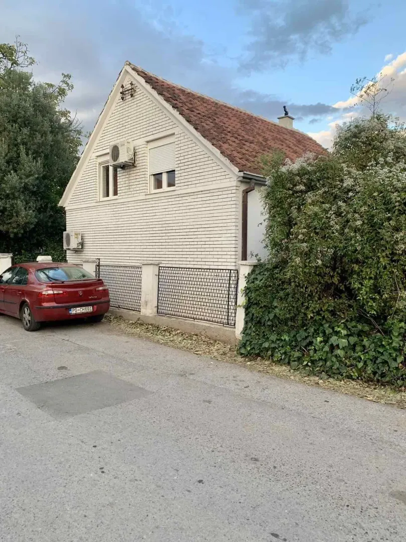 Exterior of a two-story house with a fence and a parked car.