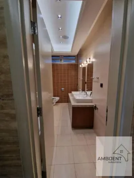 Pogled iz hodnika na prostrano kupatilo sa dva umivaonika i WC šoljom u pozadini. - image 8