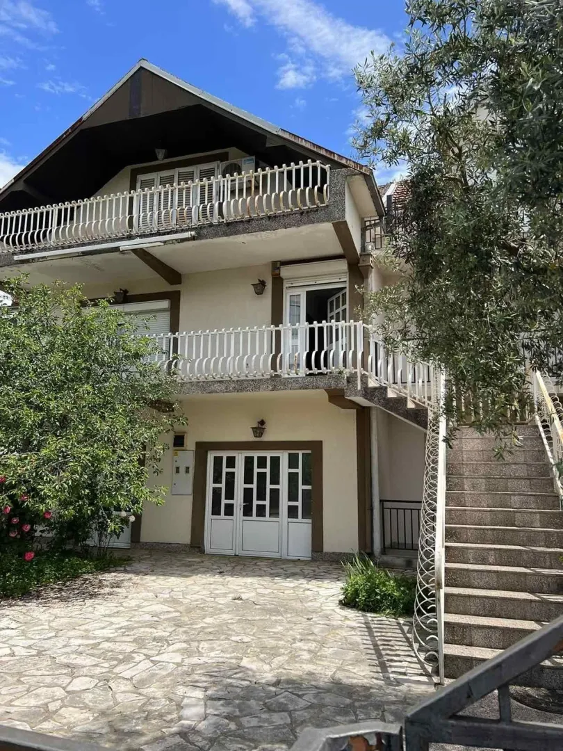 Exterior view of the house with a yard, terraces, and external stairs.