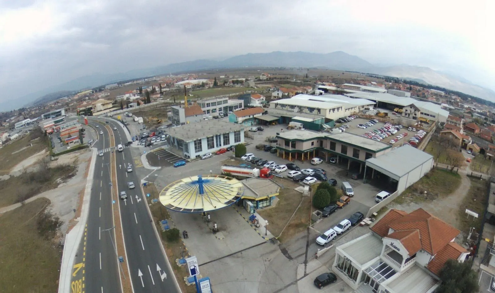 Aerial panoramic view of commercial buildings next to a main road.