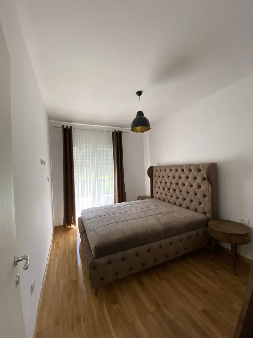 A bright bedroom with a double bed and wooden floors.