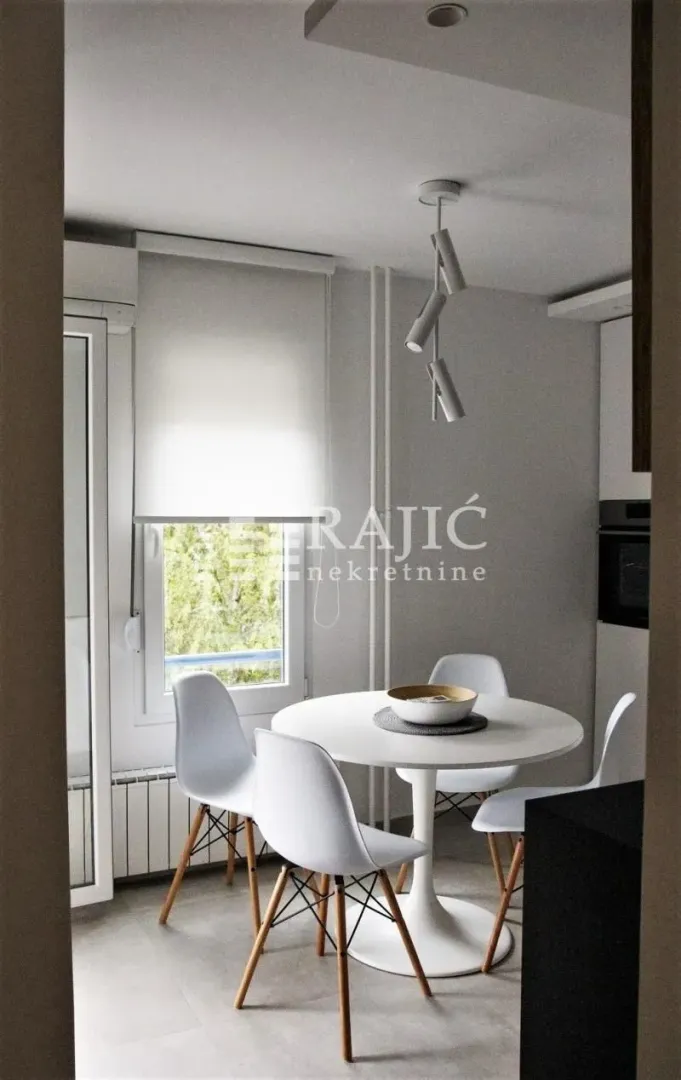 Dining area with a round table and white chairs.